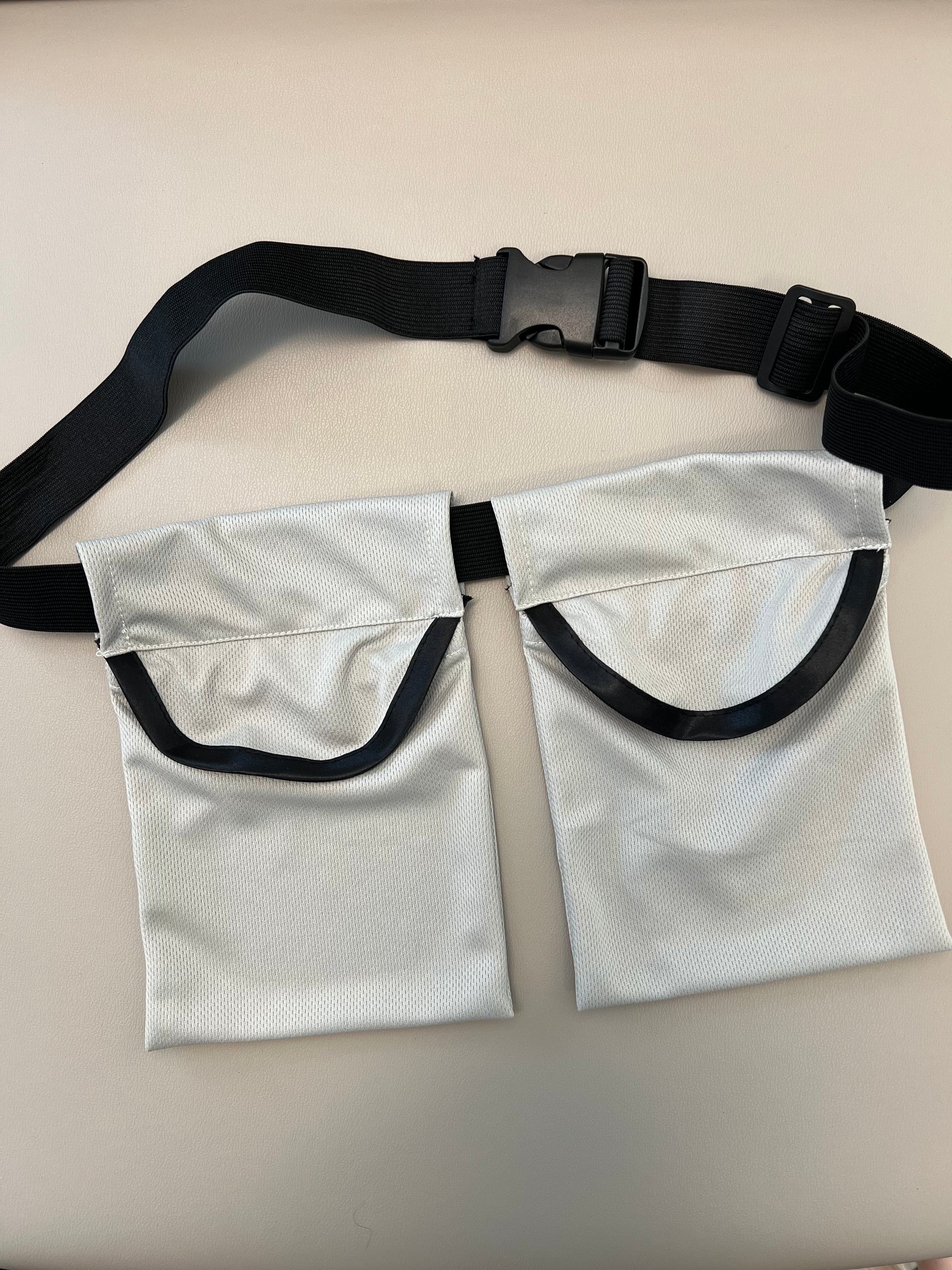 A photo of the breast reduction drain holders with a belt laying on a white table.