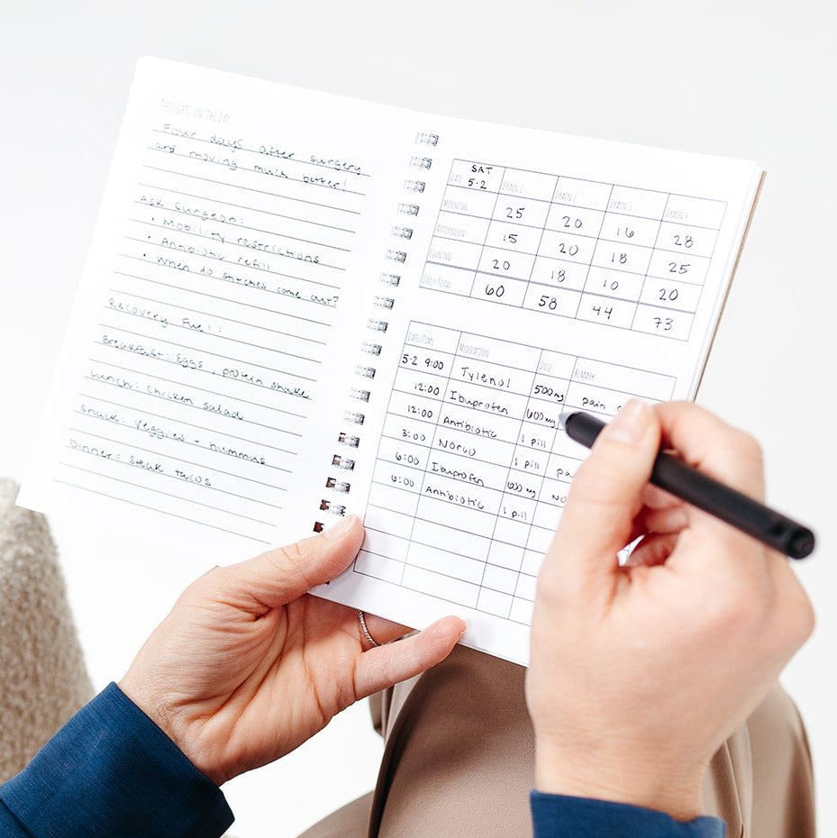 A close up of a person recording medicines and drain outputs in the Recovery Journal