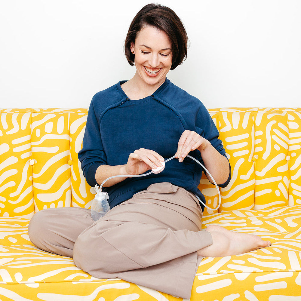 A woman clearing a JP Drain line with a Tube-Evac wearing the Mended Wing Recovery Crew on a yellow and white patterned couch.