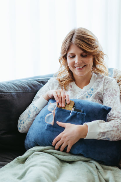 Woman using her mastectomy pillow and storing her phone and glasses in the pillow’s pocket