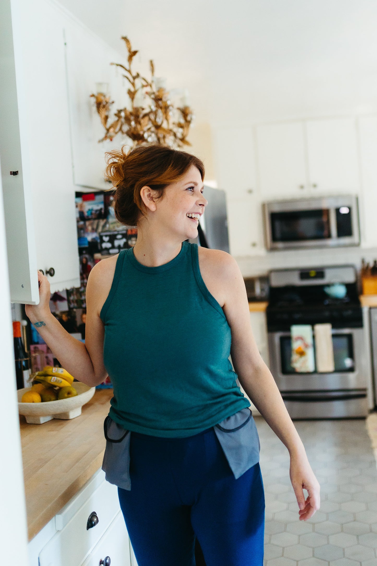 Woman wearing drain holder happily makes dinner in the kitchen after a mastectomy